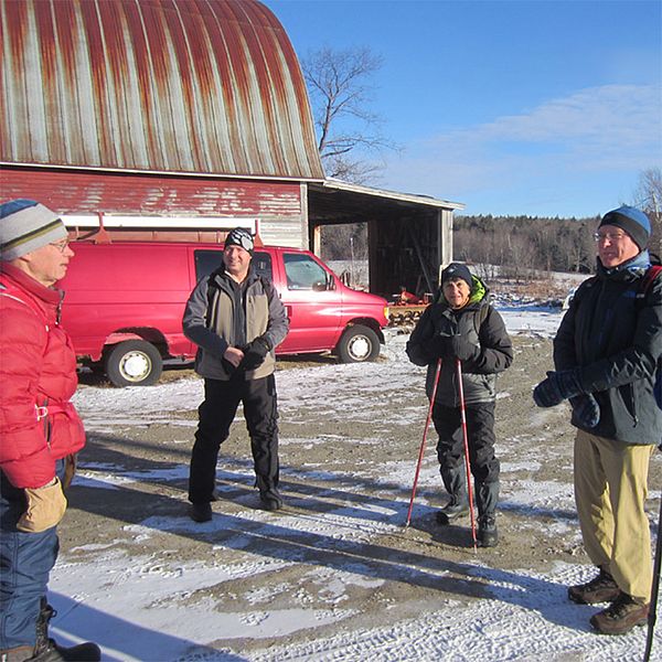A group of Keeping Track team members gather in a farm driveway in winter.